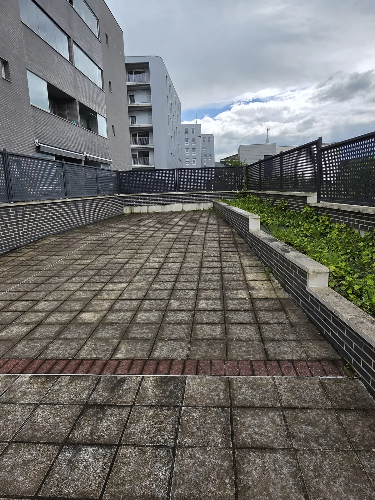Terraza comunitaria con baldosas grandes en una urbanización de Vitoria