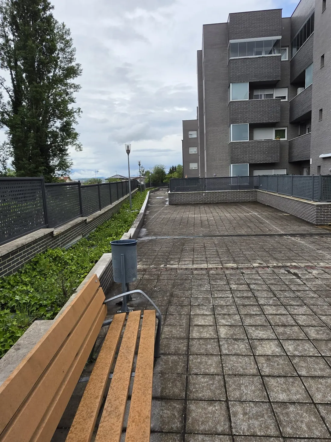 Terraza de comunidad con banco, papelera y pavimento limpio en Vitoria-Gasteiz